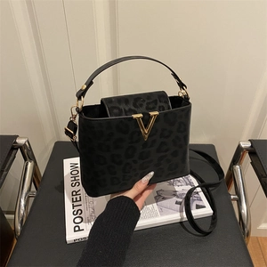 Chic black leopard print handbag with gold V-buckle and adjustable shoulder strap