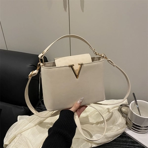 Elegant cream crossbody bag with gold V-hardware and versatile adjustable shoulder strap