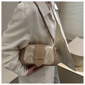 Detail of minimalist beige faux leather shoulder bag with gold clasp and textured print