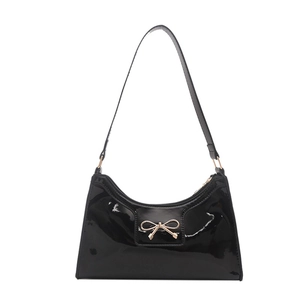 Glossy black hobo bag with a golden bow ornament and sleek crescent-shaped silhouette