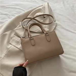 Chic khaki square handbag with vertical stripes on a stylish office blazer backdrop