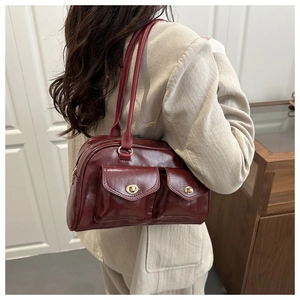 Macro shot of burgundy shoulder bag featuring front double pockets and gold turn-lock detail