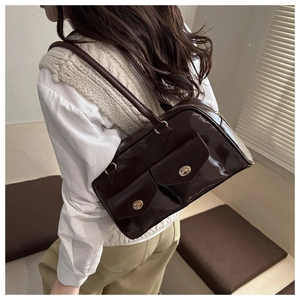 Detail of dark brown glossy leather Boston bag with dual pockets and gold twist locks