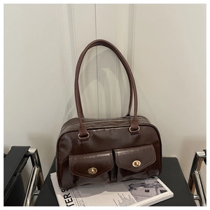 Close-up of dark brown glossy leather bag with dual front pockets and gold twist locks