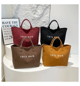 Détail de quatre sacs cabas en daim colorés en bordeaux et noir avec texte imprimé