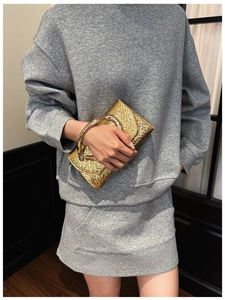 Detail of gold pleated texture evening clutch with a large circular metal ring handle