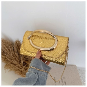 Detail of golden embossed texture and large metal ring handle on crossbody bag