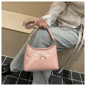 Detailed close-up of a pink bow shoulder bag with glossy finish and gold metal clasp