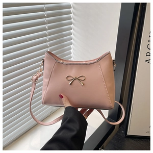 Detail of pink crossbody bag with a golden bow buckle and adjustable strap hardware