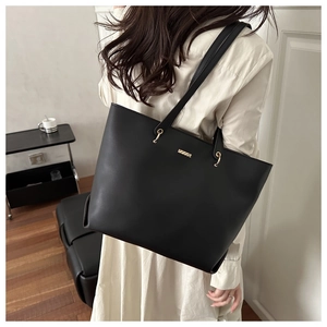 Detail of minimalist black leather tote bag with gold ring hardware and spacious interior
