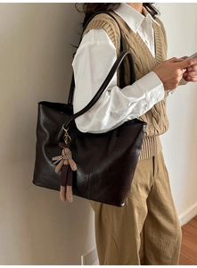 Détail du sac cabas marron foncé avec charm lapin en peluche et cuir texturé élégant