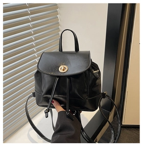 Detail of a black mini flap backpack with gold twist lock and glossy leather texture