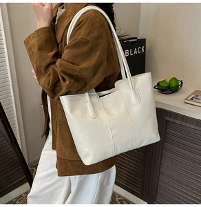 Vue détaillée d'un grand sac cabas blanc texturé porté à l'épaule sur un manteau