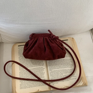 Sac bandoulière plissé bordeaux vintage style nuage sur fond de livre rétro