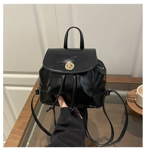 Détail du mini sac à dos noir brillant avec fermoir rotatif doré et cordon de serrage