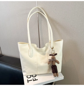 Détail du sac cabas en cuir crème avec grain subtil et breloque lapin en peluche