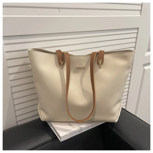 Détail du sac cabas en cuir crème avec anses brunes et anneaux dorés brillants