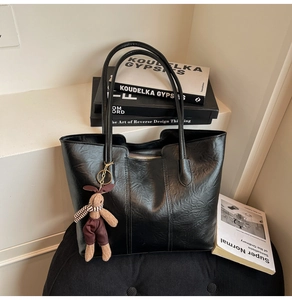 Détail du sac cabas en cuir noir texturé avec surpiqûres et breloque peluche