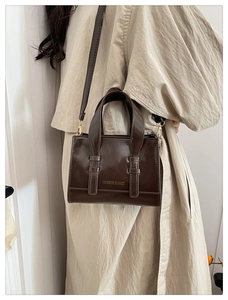 Dark brown high-gloss leather crossbody bag styled with a trench coat for work