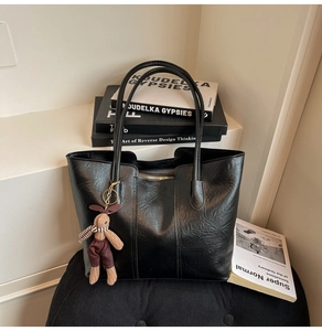 Détail du sac cabas noir texturé avec coutures verticales et un charmant lapin en peluche