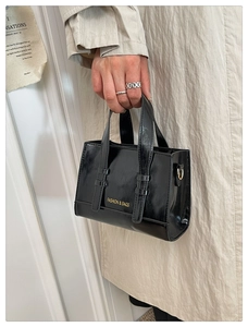 Close-up of black glossy patent tote bag with golden Fashion & Bags text and vertical straps