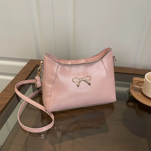 Chic pink crescent shoulder bag for women featuring a delicate gold bow accent