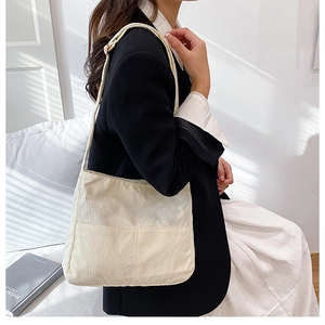 Detail of cream corduroy tote bag showing ribbed texture and practical front pocket