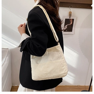 Close-up of off-white corduroy tote bag worn by a model in a minimalist setting