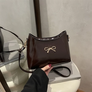 Elegant coffee brown patent leather shoulder bag with a gold metal bow decoration