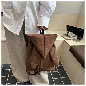 Close-up of brown suede backpack featuring bunny ear design and drawstring closure details
