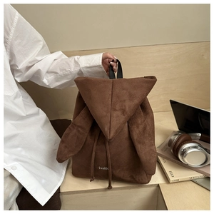 Detail of a brown suede rabbit ear backpack with drawstring closure and fashion logo