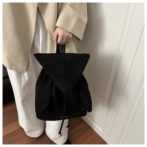 Macro detail of black matte suede backpack featuring a triangle flap and drawstring closure