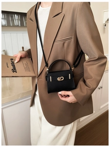 Close-up of black lychee grain mini handbag featuring elegant gold twist lock and shoulder strap