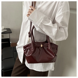 Détail du sac seau bordeaux brillant avec cuir plissé et bandoulière réglable