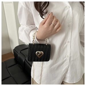Detail of black woven mini bag with gold heart clasp and faux pearl handle