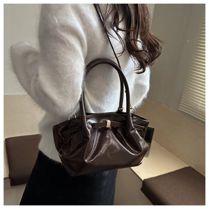 Détail du sac seau en cuir marron foncé avec design nœud et boucle dorée