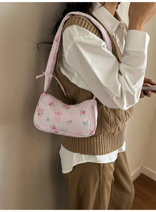 Detailed texture of pink floral canvas hobo bag with red flowers and bow patterns