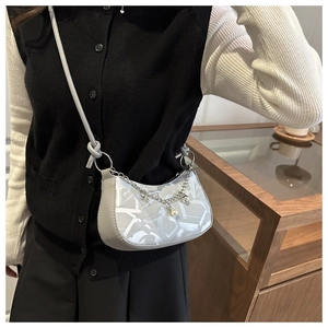 Détail du sac bandoulière gris avec imprimé graffiti et chaîne à perles et cœur