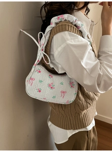 Detail of floral underarm bag with pink roses, red bows, and tied shoulder strap