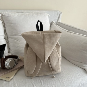 Minimalist beige corduroy backpack with long rabbit ears on a soft white sofa