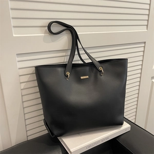 Sac fourre-tout minimaliste en similicuir noir avec plaque dorée sur fond de fenêtre