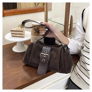 Detailed close-up of dark brown suede handbag featuring vintage buckle and side pleats
