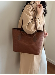 Détail d'un sac cabas tissé marron avec lanières en cuir sur un trench kaki
