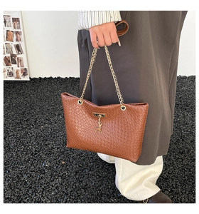 Close-up of brown woven texture PU leather tote with gold chains and deer pendant detail
