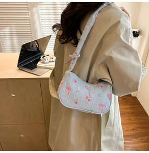 Detail of light blue quilted shoulder bag with floral patterns and pink ribbon motifs