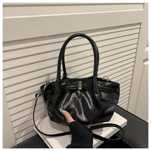 Dettaglio borsa tote nera lucida con fibbia dorata e tracolla sottile in pelle nera