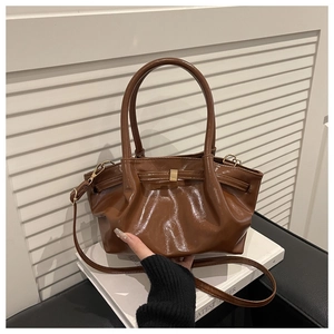 Dettaglio di una borsa a secchiello in pelle marrone lucida con hardware dorato