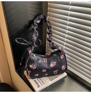 Close-up of floral quilted baguette bag with ruffled strap and ribbon details