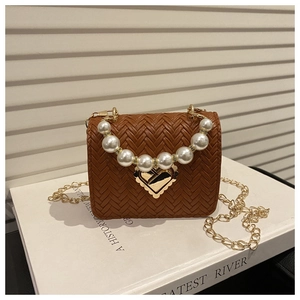 Details einer braunen Webleder-Tasche mit Herzschloss aus Gold und Perlengriff