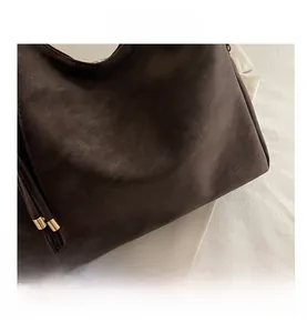 Detailed top view of dark brown pebbled leather texture with gold foil stamped logo